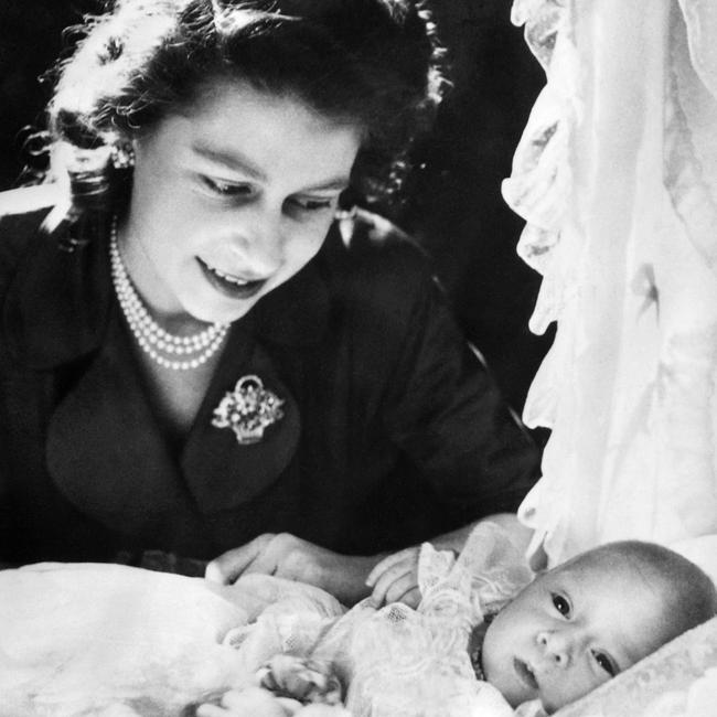 The then Princess Elizabeth bends over baby Prince Charles in 1949. Picture: AFP