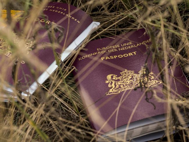 Two Dutch passports lie in a field amongst luggage, personal belongings and wreckage from Malaysia Airlines flight MH17