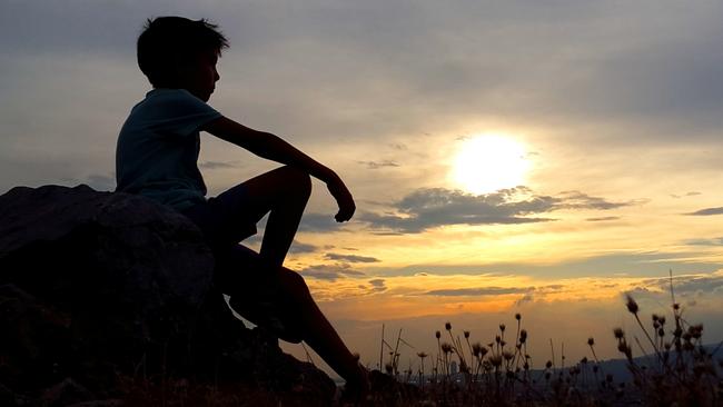 Relaxed boy on hill.