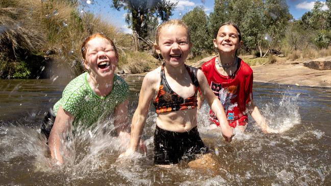 Maddie, Harper and Nyah Walker cool off in the shallows of a secret waterhole hidden in Warrumbungle National Park. Picture: Liam Mendes