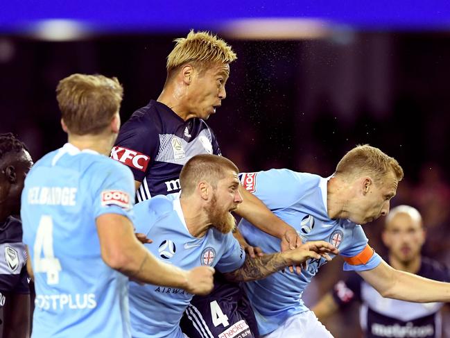 Melbourne Victory captain Japan's Keisuke Honda (top) rises over Melbourne City players to score his first goal in Australia during their A-League football match in Melbourne on October 20, 2018. (Photo by WILLIAM WEST / AFP) / IMAGE RESTRICTED TO EDITORIAL USE - STRICTLY NO COMMERCIAL USE