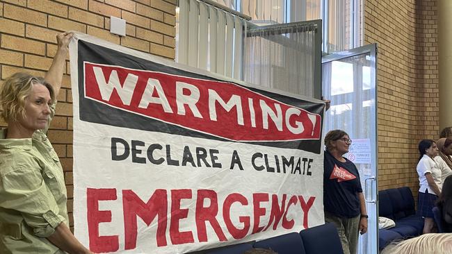 Members from the Coffs Coast Climate Action Group raised this sign during discussion, just moments before the emergency was recognised at the council meeting on Thursday, December 8, 2022. Picture: Matt Gazy