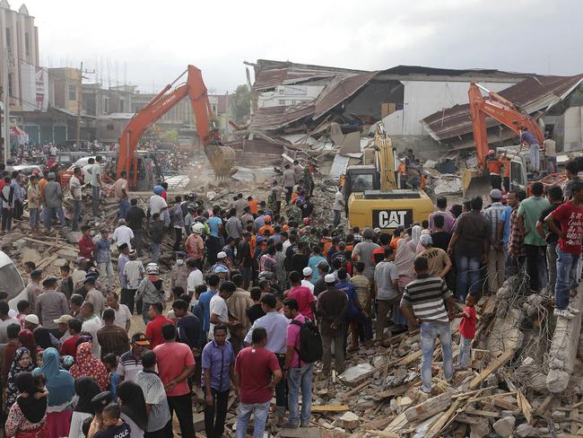 Rescuers use excavators to search for victims under the rubble of collapsed buildings after an earthquake in Pidie Jaya, Aceh. Picture: AP