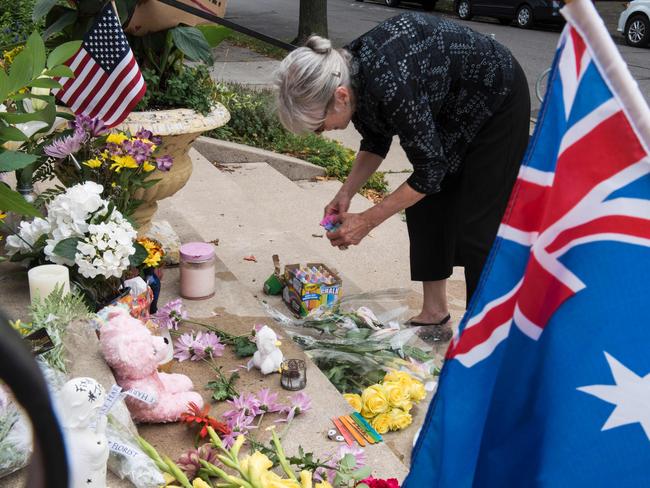 A friend places flowers and signs at a makeshift memorial for Justine Damond, who was killed by a police officer responding to her emergency call. Picture: AFP / STEPHEN MATUREN