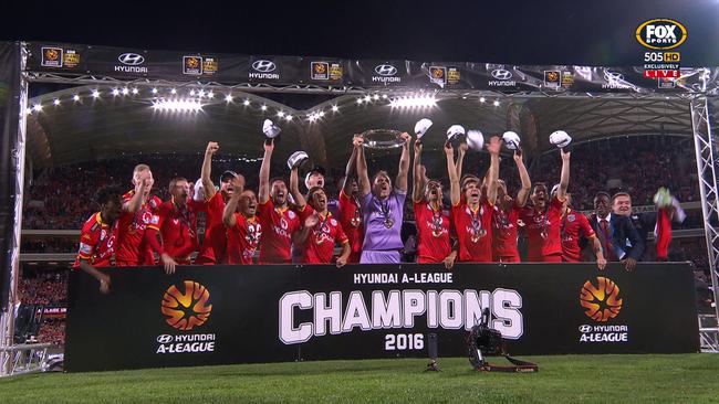 Adelaide United players lift the A-League championship trophy.