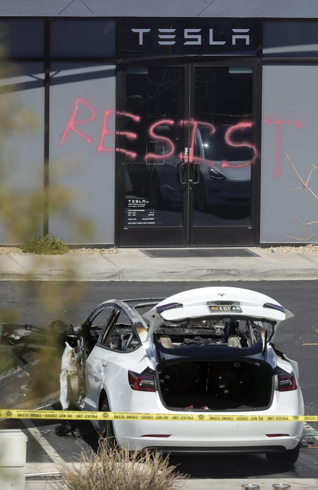 A burned out Tesla sits in front of the graffitied Tesla Collision Centre in Las Vegas. Picture: Steve Marcus/Las Vegas Sun via AP