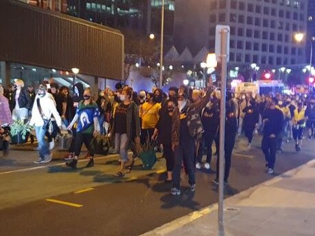 Protesters march to the police headquarters in Roma Street.