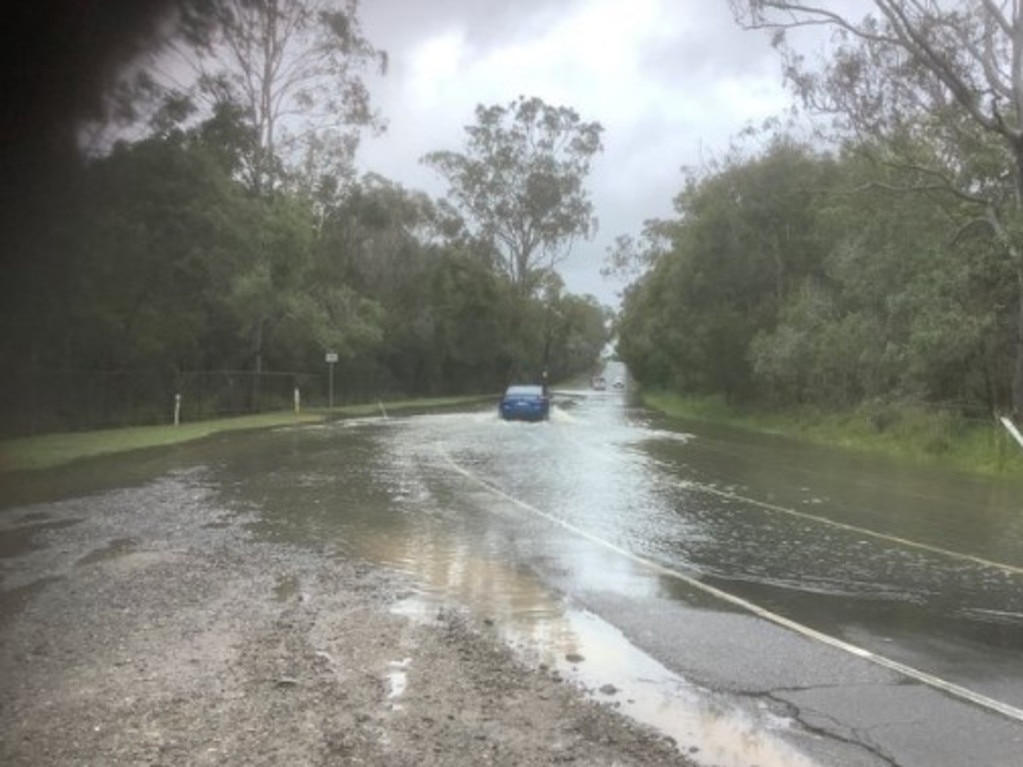 A car drives through floodwaters over a road at Karawatha on Brisbane's southside Picture: Qld Police