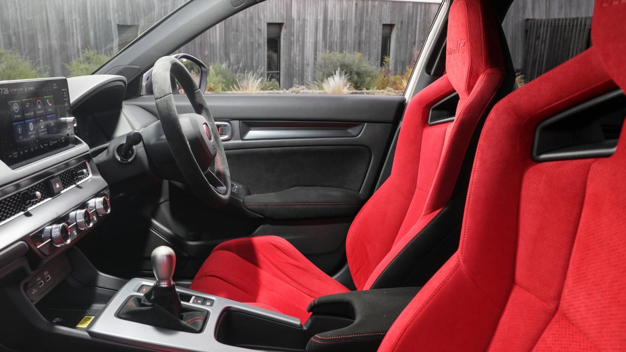 Matching the red Honda badge and brake calipers on the outside, the Honda Civic Type R interior features front bucket seats, carpet and seat belts all in red.