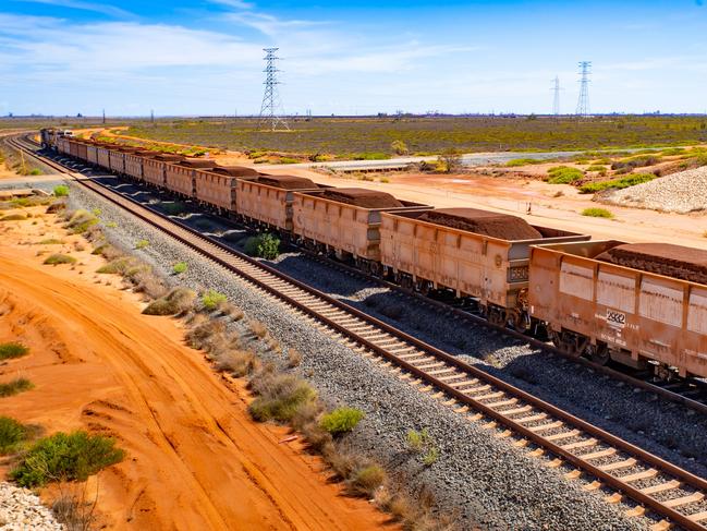 A freight train carrying iron ore travels along a rail track towards Port Hedland, Australia, on Monday, March 18, 2019. A two-day drive from the nearest big city, Perth, Port Hedland is the nexus of Australias iron-ore industry, the terminus of one of Australias longest private railways that hauls ore about 400 kilometers (250 miles) from the mines of BHP Group and Fortescue Metals Group Ltd. The line ran a record-breaking test train weighing almost 100,000 tons that was more than 7 kilometers long in 2001, and even normal trains haul up to 250 wagons of ore. Photographer: Ian Waldie/Bloomberg via Getty Images