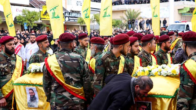 Hezbollah fighters stand by the coffins of a fellow fighter and of one of his relatives who were killed in Israeli bombardment.