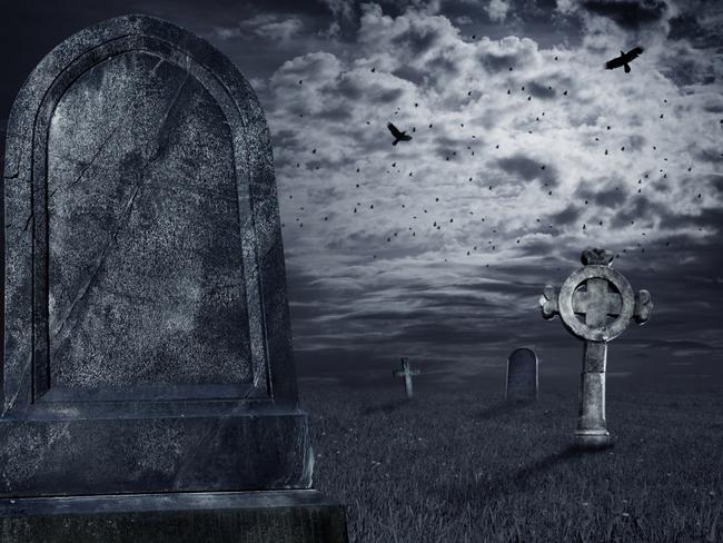 Old tombstone with a dark sky. Graves with gloomy sky and birds flying. Halloween theme. Black and white. Picture: iStock