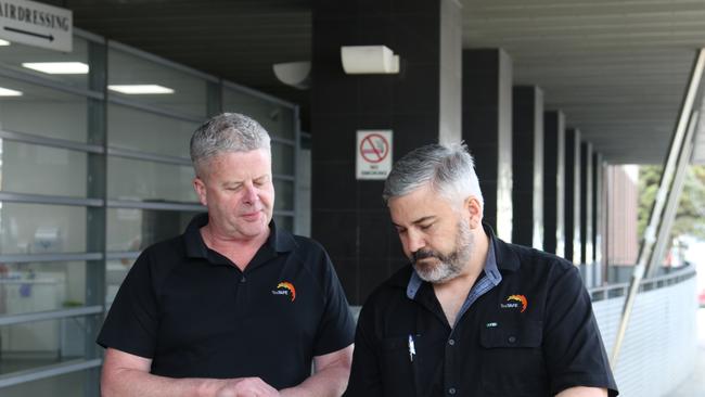 TasTAFE automotive teacher Tristan Sabol reads independent air quality monitoring report to a colleague outside TAFE following carbon monoxide poisoning incident. Picture: Elise Kaine