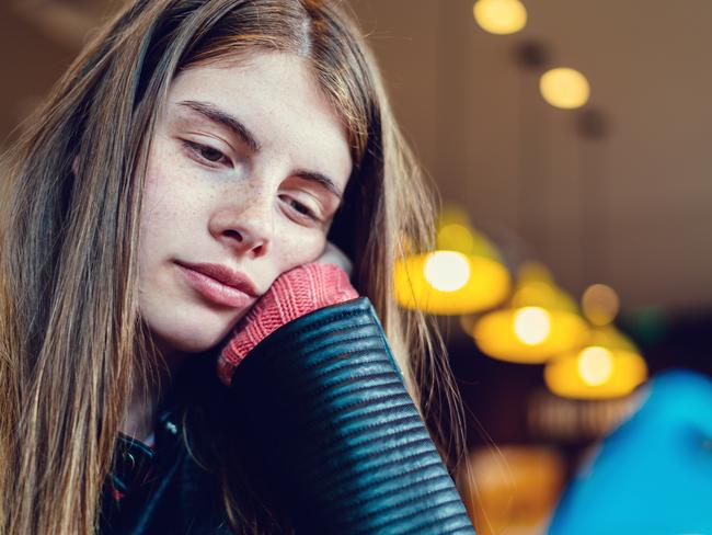 Teenage girl in cafe text messaging on smartphone