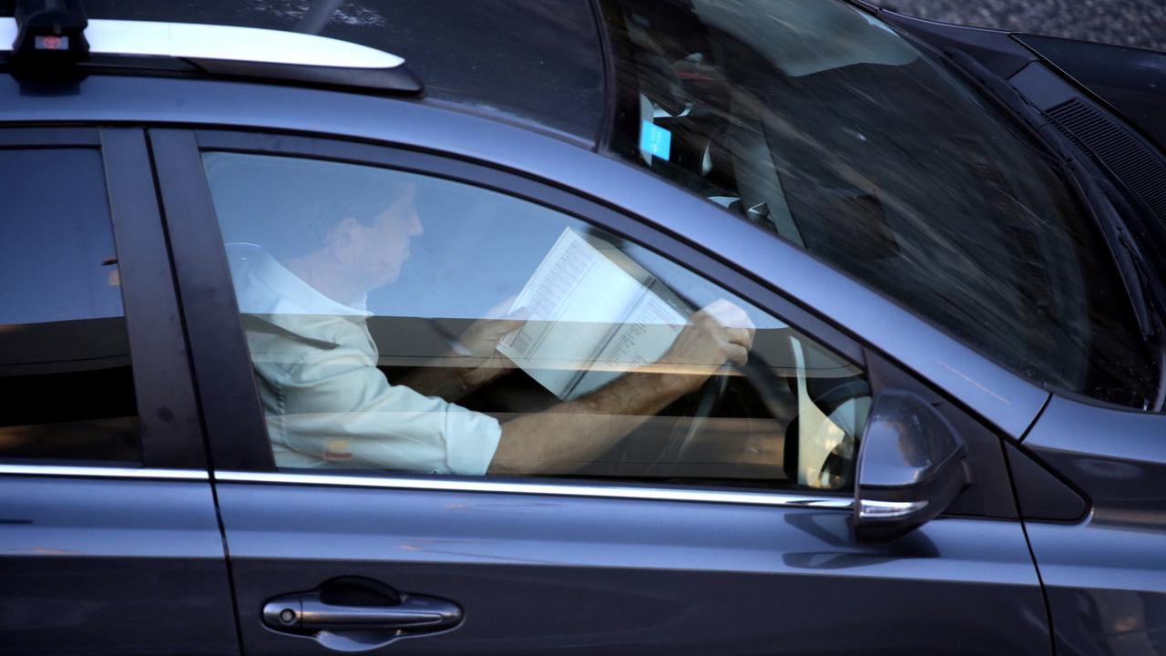 A driver reads in traffic on Manly Rd. Picture: John Grainger