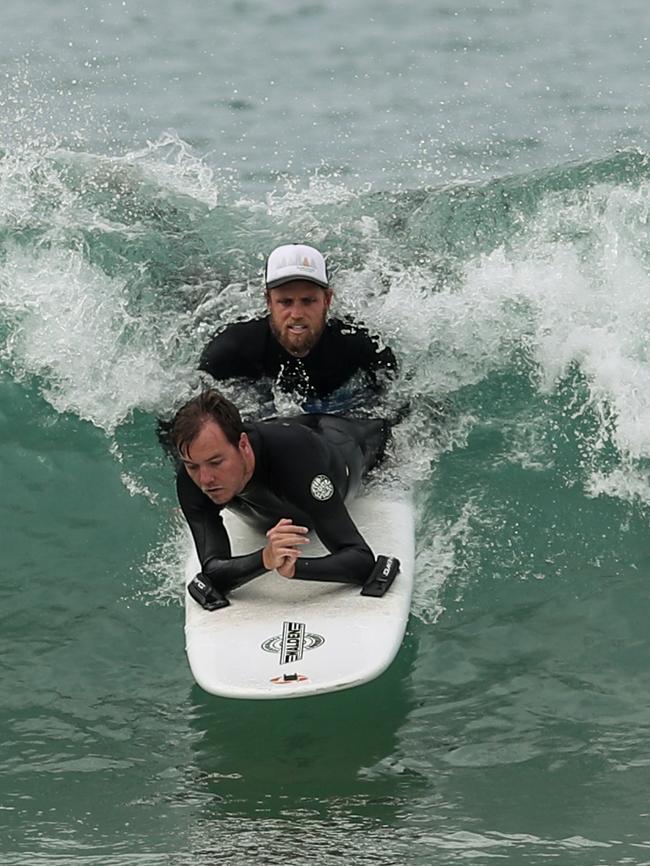 Mr Leslie catches a wave with his carer. Picture: Julian Andrews/AAP