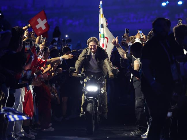 PARIS, FRANCE - AUGUST 11: American Actor and Film Producer Tom Cruise rides on a Motorbike with the IOC Flag during the Closing Ceremony of the Olympic Games Paris 2024 at Stade de France on August 11, 2024 in Paris, France. (Photo by Jamie Squire/Getty Images)