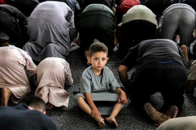 A boy looks on during early morning prayers for Eid al-Adha