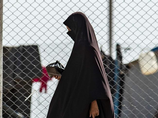 A picture taken on October 17, 2019 shows a woman walking near a fence at the Kurdish-run al-Hol camp for the displaced where families of Islamic State (IS) foreign fighters are held, in the al-Hasakeh governorate in northeastern Syria. (Photo by Delil SOULEIMAN / AFP)