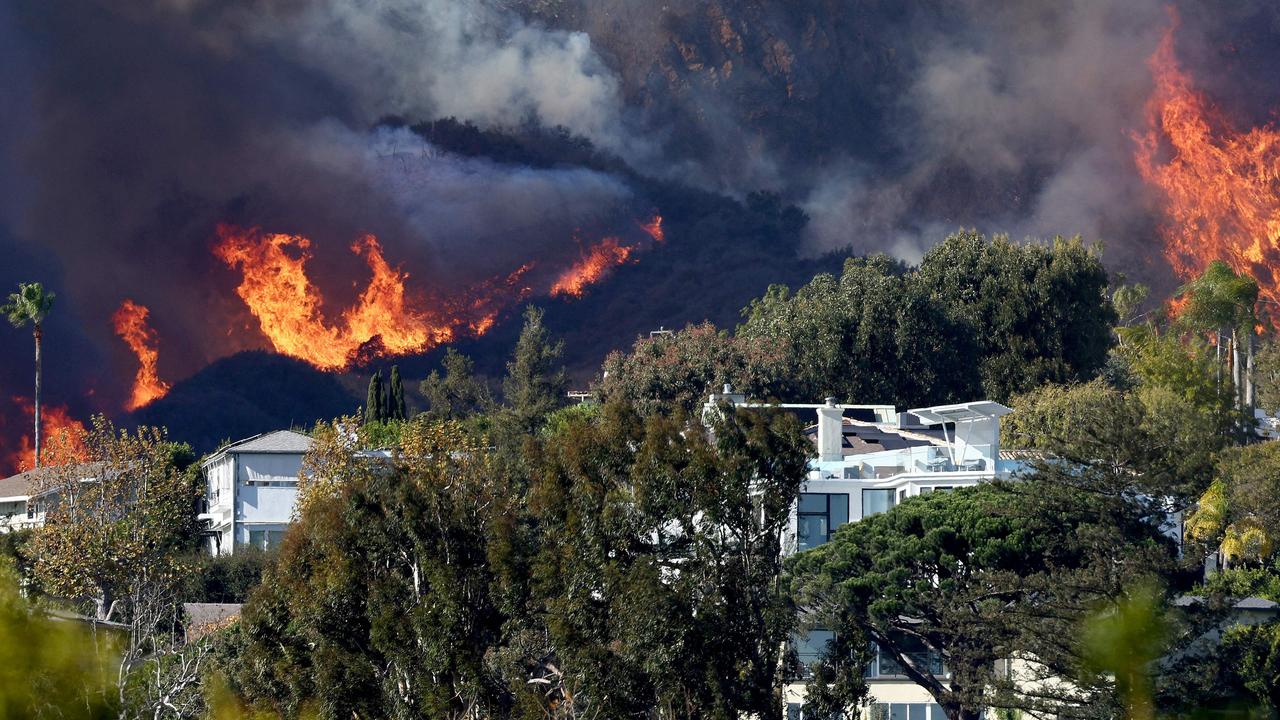 The Palisades Fire burns near homes amid a powerful windstorm. Picture: AFP