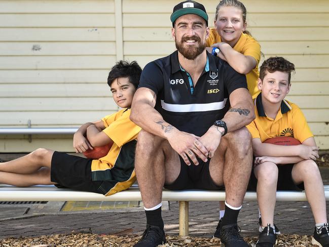 Port Adelaide key forward Charlie Dixon at Evanston Gardens Primary School with students, Tobey Dwyer 12, Mia Small 12 and Casey Dawes 12.Tuesday, February 11, 2020. Pic. Roy VanDerVegt