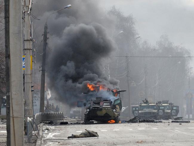 CORRECTION / TOPSHOT - This photograph taken on February 27, 2022 shows a Russian Armoured personnel carrier (APC) burning next to unidentified soldier's body during fight with the Ukrainian armed forces in Kharkiv. - Ukrainian forces secured full control of Kharkiv on February 27, 2022 following street fighting with Russian troops in the country's second biggest city, the local governor said. (Photo by Sergey BOBOK / AFP) / âThe mention [next to unidentified soldier's body] has been added to the caption and the erroneous mention[s] appearing in the metadata of this photo by Sergey BOBOK has been modified in AFP systems in the following manner: [February 27] instead of [February 26]. Please immediately remove the erroneous mention[s] from all your online services and delete it (them) from your servers. If you have been authorized by AFP to distribute it (them) to third parties, please ensure that the same actions are carried out by them. Failure to promptly comply with these instructions will entail liability on your part for any continued or post notification usage. Therefore we thank you very much for all your attention and prompt action. We are sorry for the inconvenience this notification may cause and remain at your disposal for any further information you may require.â