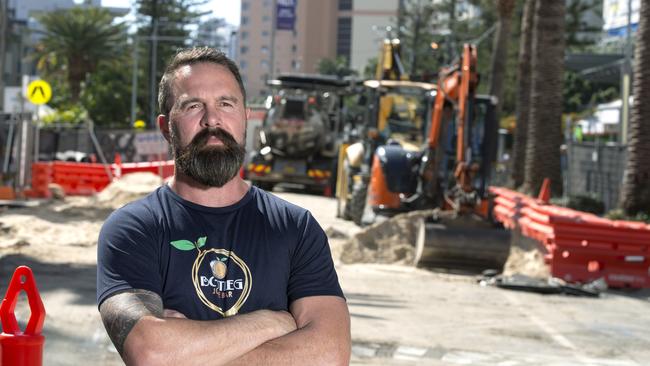 Bootleg Juice Bar owner Anthony Bootleg, posing on Surf Parade last year, wasn’t happy about a 30 per cent plus drop in trading since council's major upgrade started — now he’s fuming at a plan to using paving paint on the private side of the footpath to match new concreting on the public side. Photo: Jerad Williams