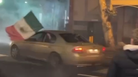 A passenger in the car holds a Mexican flag.