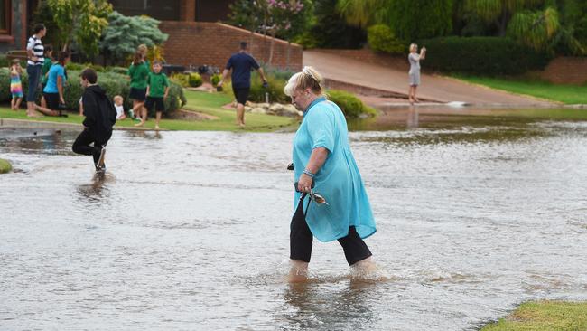 Willow Drive residents wade through the floods over the road at Paradise. Picture: Roger Wyman