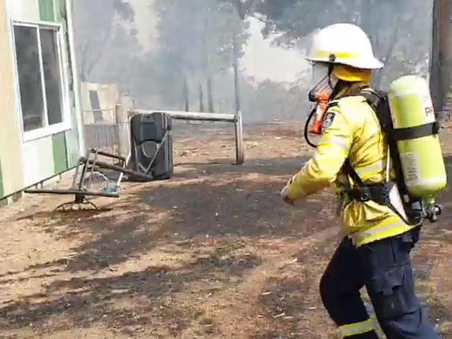 Former Australian prime minister Tony Abbott, wearing breathing apparatus, rushes towards a burning house at Bendalong, while fighting fires with the Rural Fire Service on the NSW south coast. Picture: Ingleside RFS