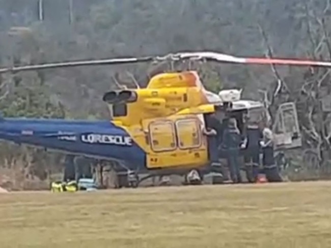 Emergency services load the two men into the RACQ CQ Rescue chopper.