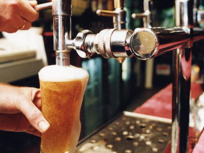 Publican John Jenkins behind the bar at the Aldgate Pump Hotel pouring a glass of tap beer.  Used 
