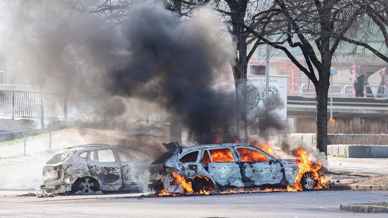 Two cars burn in a parking lot during rioting in Norrkoping, Sweden. Photo by Stefan JERREVANG / various sources / AFP)