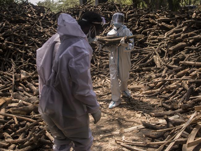 Cemetery workers wearing PPE kits sort logs of wood for the funeral pyres to perform the last rites of the patients who died of the coronavirus disease at a crematorium in the outskirts of New Delhi, India. Picture: Getty Images