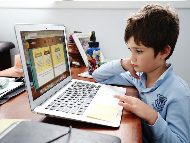 Phoenix Crawford does schoolwork on a laptop while being home-schooled by his mother, Donna Eddy, in Sydney earlier this month. Picture: Getty Images