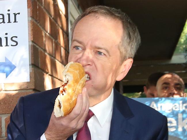 Labor leader Bill Shorten tucks into a snag – an election day favourite the Coalition warns could cost a lot more under his carbon pollution plan. Picture: Kym Smith