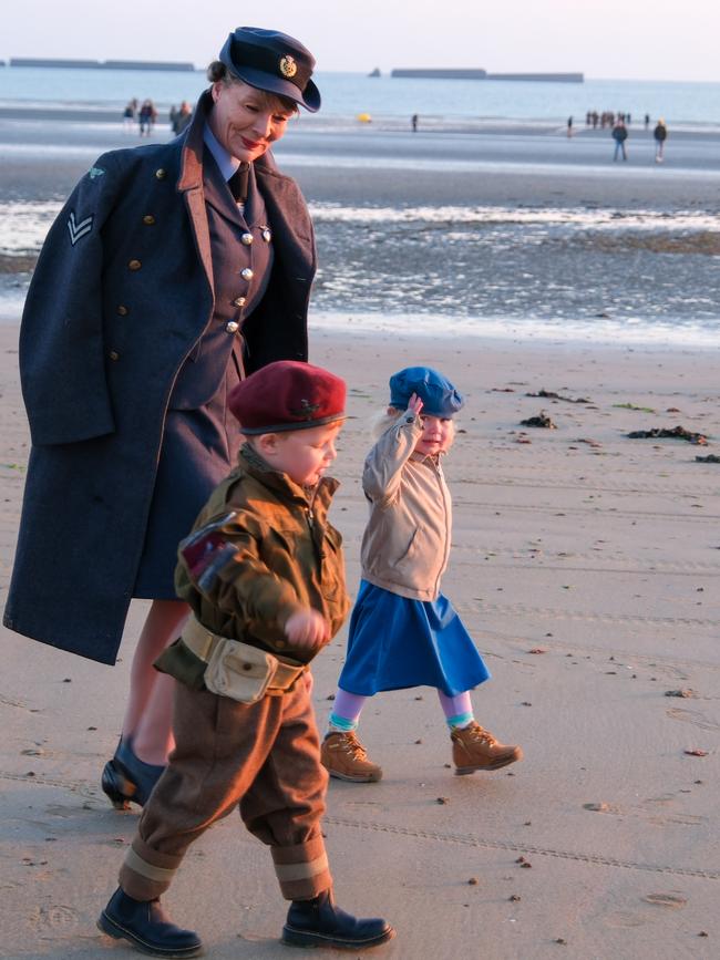 A military family walks on Arromanches-les-bains in Normandy as dawn breaks on the 80th anniversary of D-Day. Picture: Jacquelin Magnay.