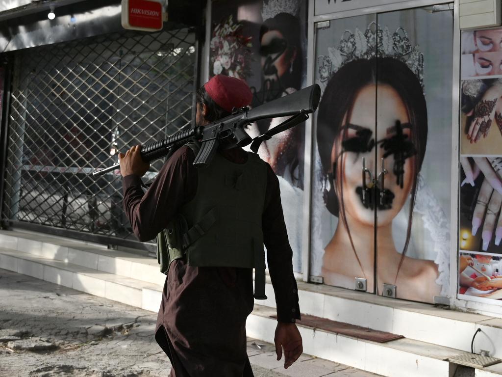 A Taliban fighter walks past a beauty salon in Kabul. Picture: Wakil Koshar/AFP