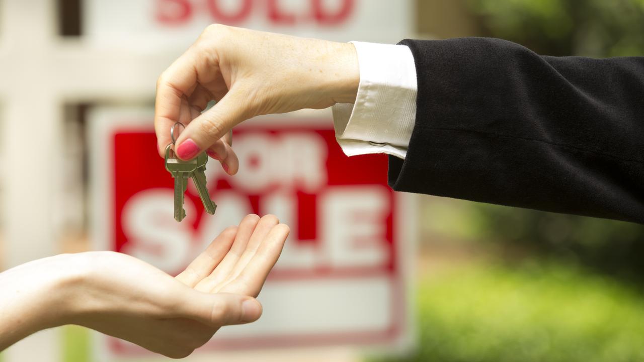 Real estate agent hands keys to buyer in generic real estate photo.