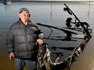 BURNT DREAMS: Errol Lindsay surveys the charred remains of his fishing boat at Lake Cootharaba. Picture: John McCutcheon