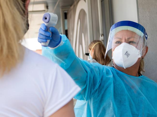 TOPSHOT - A health worker takes a patient's temperature before sending them to a tent to be tested at a COVID-19 testing site at St. John's Well Child and Family Center, amid the novel coronavirus pandemic, July 24, 2020, in Los Angeles, California. - The coronavirus pandemic hit grim new milestones July 23, with cases topping four million in the United States and three million in Europe as fresh spikes from Belgium to Tokyo to Melbourne forced new restrictions on citizens. (Photo by VALERIE MACON / AFP)