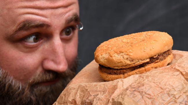 Casey Dean inspects a McDonald's burger bought in 1995 and kept in an Australian shed for years which has never decomposed.