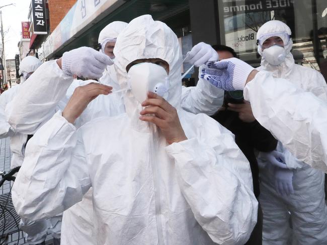 Workers prepare protective clothing to spray disinfectant on a shopping street in Seoul, South Korea. Picture: AP