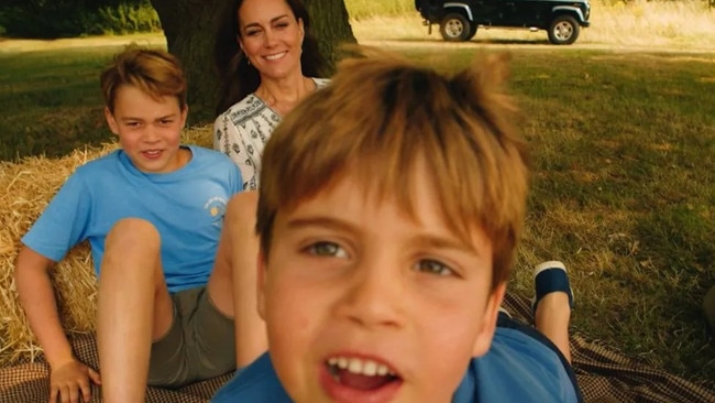 Princes Louis and George play in front of the video camera while their mother Catherine looks on in this scene.