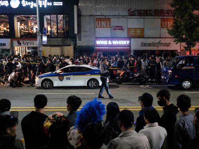 Onlookers watch as a policeman patrols after a Halloween stampede in the district of Itaewon in Seoul. Picture: AFP