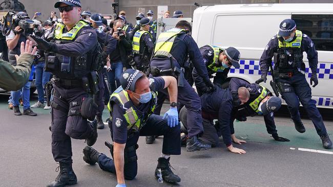 Police round up protesters outside Parliament House in Melbourne on Sunday. Picture: AAP