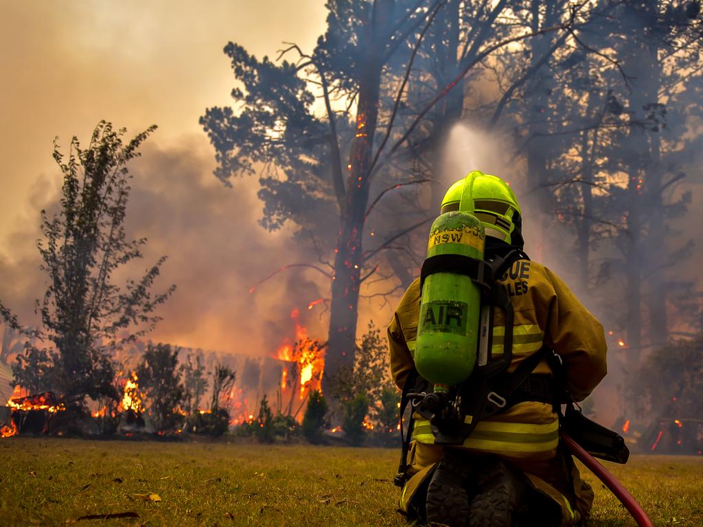 An out of control fire ripped through the Blue Mountains this afternoon. Unknown houses and other property has been destroyed along Bells Line of Road from Bilpin to Mount Tomah and further west. A firefighter continues to cool and protect the surroundings of the industrial shed destroyed. Picture: Matrix