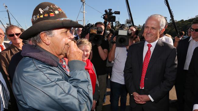 Uncle Ossie Cruse plays a gum leaf as he greets local people during a walk on the wharf at the port in Eden with then Prime Minister Malcolm Turnbull. Picture: Lyndon Mechielsen