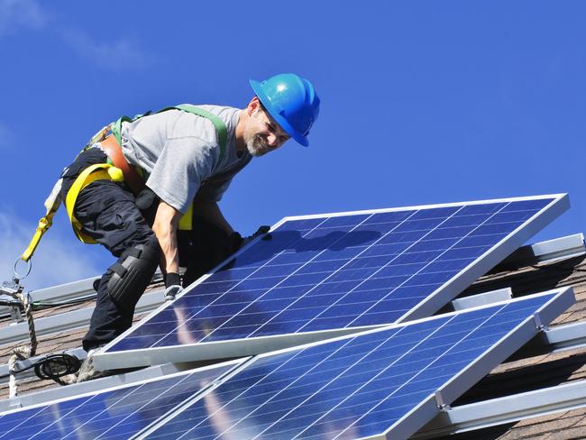 Man installing alternative energy photovoltaic solar panels on roof