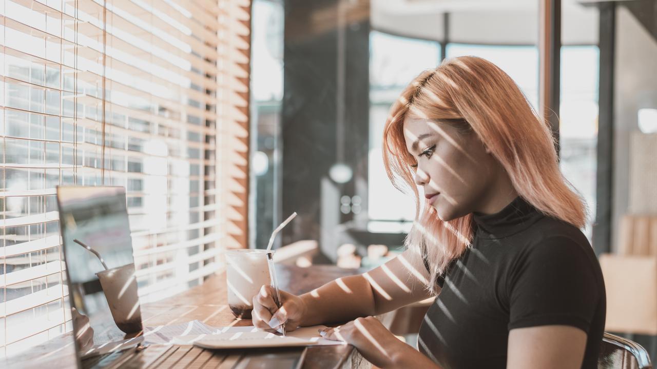 A young worker sets up her laptop in a cafe. Picture: iStock